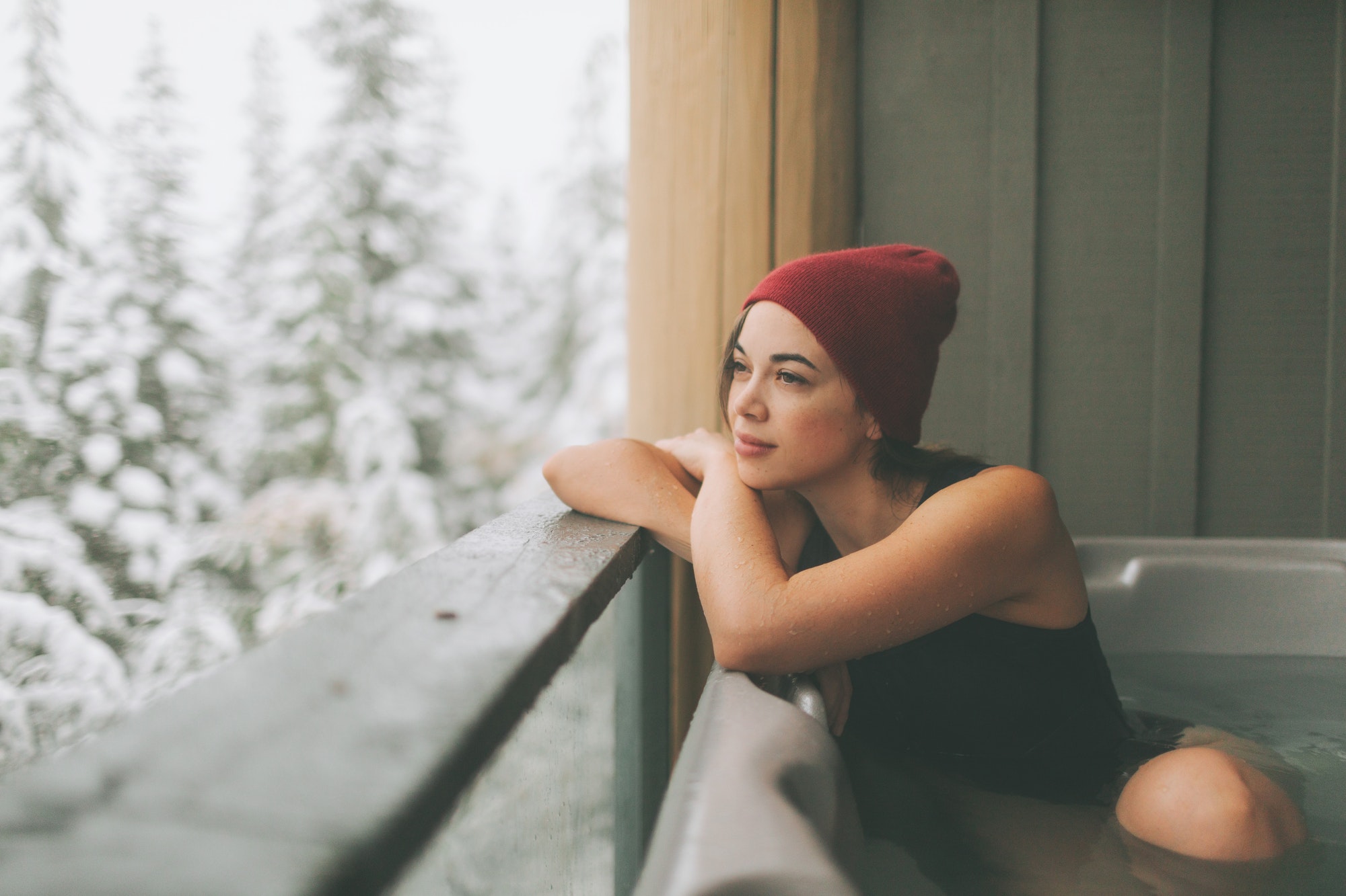 Woman sitting in a hot tub, looking out at a snowy winter view.